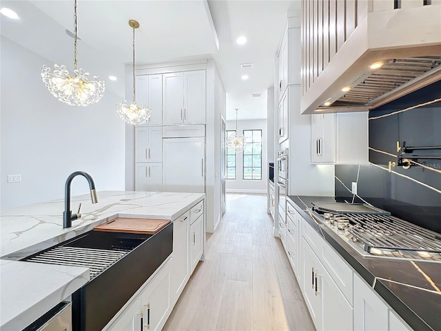 kitchen featuring dark stone countertops, pendant lighting, custom exhaust hood, an inviting chandelier, and white cabinetry