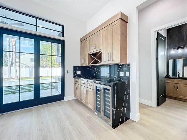 bar featuring wine cooler, backsplash, sink, and light hardwood / wood-style flooring