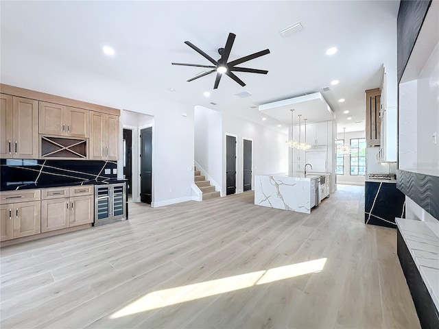 kitchen featuring light hardwood / wood-style flooring, ceiling fan with notable chandelier, tasteful backsplash, and hanging light fixtures