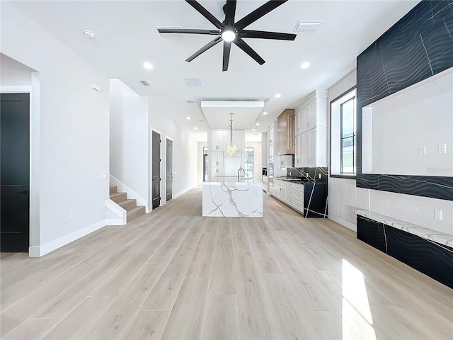 unfurnished living room with light hardwood / wood-style floors, sink, and ceiling fan