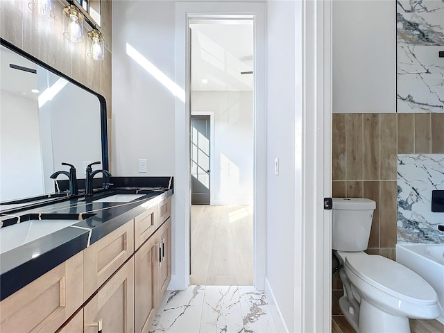 bathroom with toilet, vanity, and tile walls