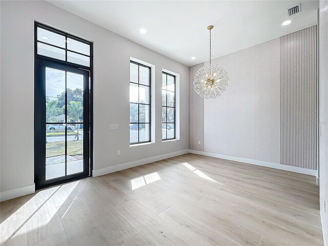 empty room featuring a chandelier and light wood-type flooring