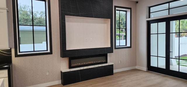 doorway to outside with french doors, a large fireplace, and light hardwood / wood-style flooring