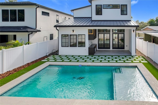 rear view of property with a fenced in pool and a patio area