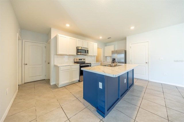 kitchen featuring a kitchen island with sink, white cabinets, decorative backsplash, light stone countertops, and stainless steel appliances