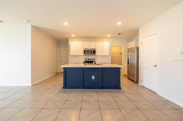 kitchen with appliances with stainless steel finishes, sink, white cabinetry, and an island with sink