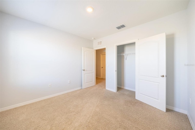 unfurnished bedroom with light colored carpet and a closet