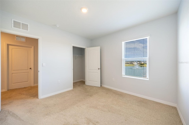 unfurnished bedroom with light carpet and a closet