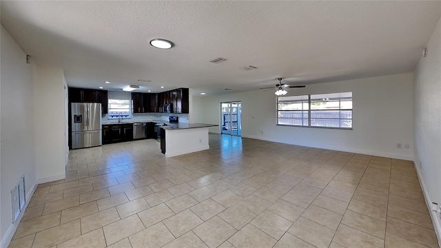 kitchen featuring ceiling fan, light tile patterned floors, a healthy amount of sunlight, and appliances with stainless steel finishes