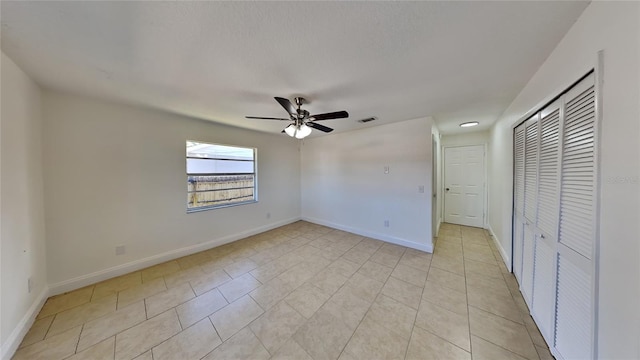 unfurnished bedroom featuring ceiling fan, a closet, and light tile patterned floors