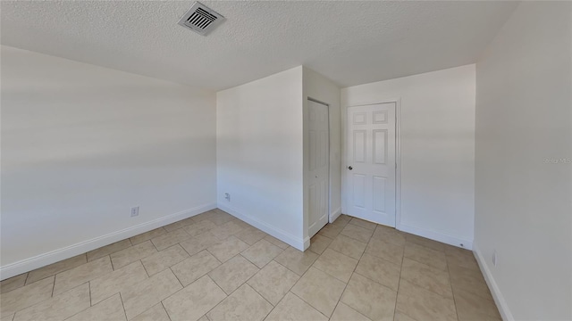 tiled empty room featuring a textured ceiling