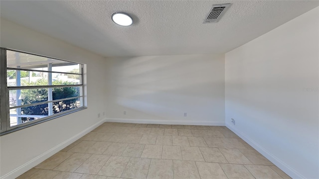 spare room featuring light tile patterned floors and a textured ceiling