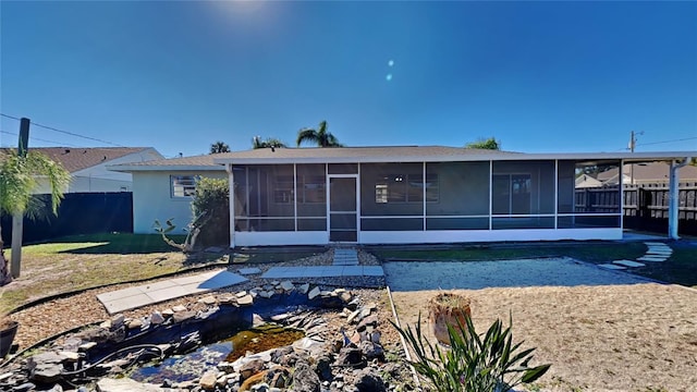 back of property featuring a lawn and a sunroom