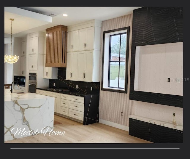 kitchen featuring pendant lighting, dark stone counters, white cabinets, double oven, and a chandelier