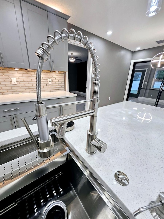 kitchen featuring tasteful backsplash, gray cabinets, and sink