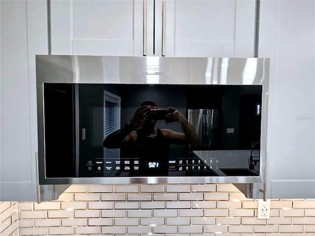 details featuring tasteful backsplash and white cabinetry