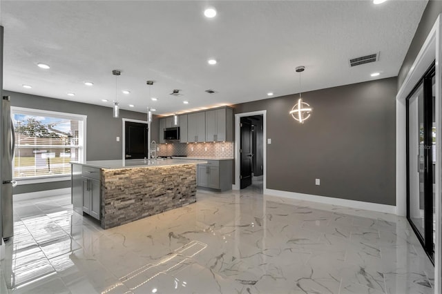 kitchen featuring tasteful backsplash, hanging light fixtures, and gray cabinetry