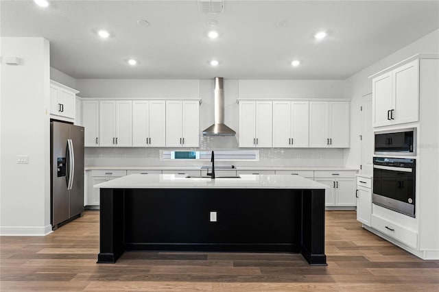 kitchen featuring a kitchen island with sink, dark hardwood / wood-style flooring, wall chimney exhaust hood, and appliances with stainless steel finishes