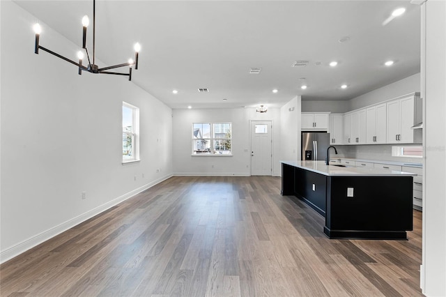 kitchen with a center island with sink, white cabinets, sink, light hardwood / wood-style floors, and stainless steel fridge with ice dispenser