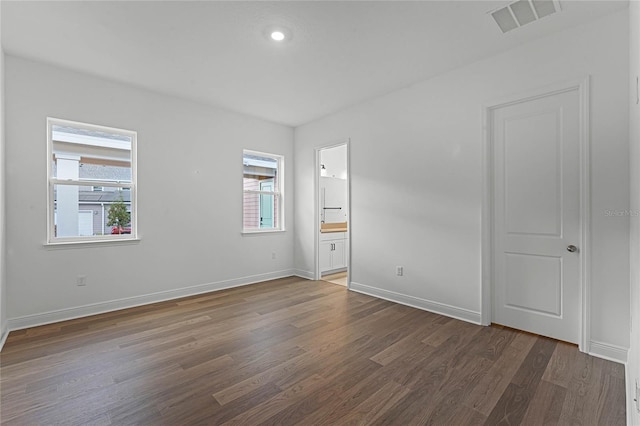 unfurnished bedroom featuring ensuite bathroom and dark hardwood / wood-style floors