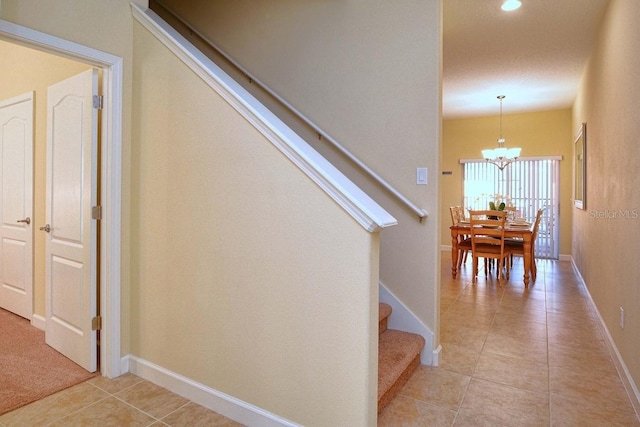 staircase featuring tile patterned floors and a notable chandelier