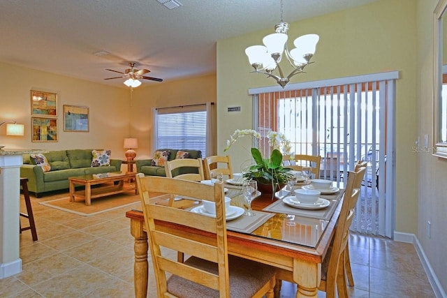 dining space with ceiling fan with notable chandelier, light tile patterned floors, and a textured ceiling