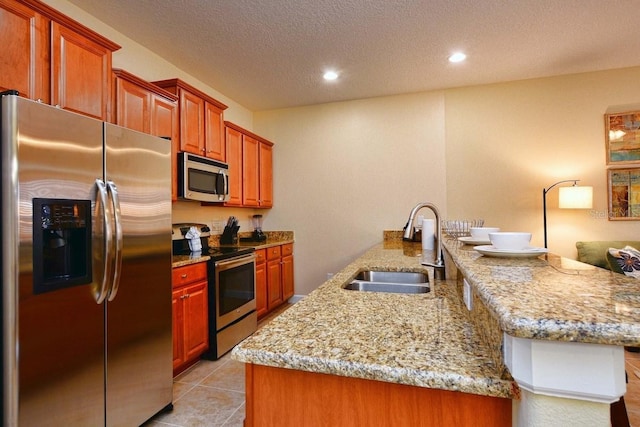 kitchen featuring kitchen peninsula, a textured ceiling, stainless steel appliances, sink, and light tile patterned flooring