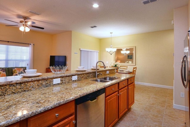 kitchen featuring pendant lighting, ceiling fan with notable chandelier, sink, stainless steel dishwasher, and light stone countertops