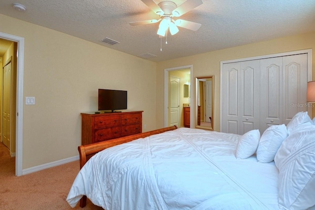 carpeted bedroom with ceiling fan, a closet, and a textured ceiling