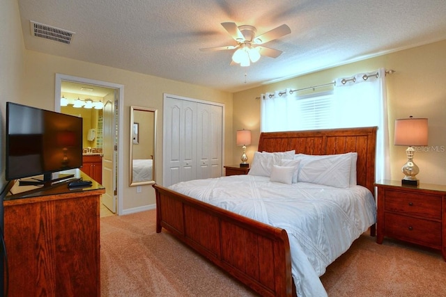 carpeted bedroom with a textured ceiling, ensuite bathroom, and ceiling fan