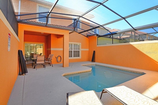 view of swimming pool featuring glass enclosure and a patio