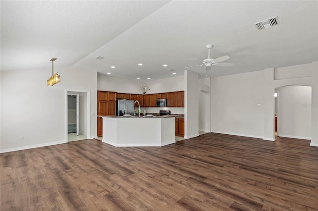 kitchen featuring appliances with stainless steel finishes, dark hardwood / wood-style flooring, pendant lighting, ceiling fan, and a kitchen island with sink