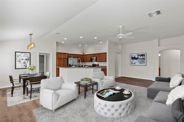 living room with wood-type flooring, lofted ceiling, a textured ceiling, and ceiling fan