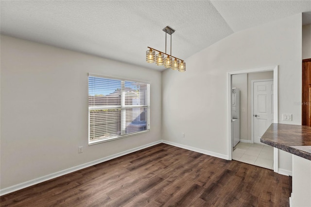 unfurnished dining area with vaulted ceiling, hardwood / wood-style floors, and a textured ceiling