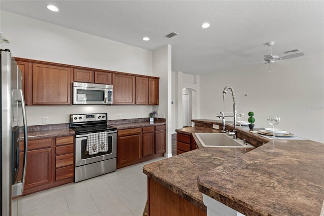 kitchen featuring sink, a textured ceiling, light tile patterned floors, appliances with stainless steel finishes, and ceiling fan