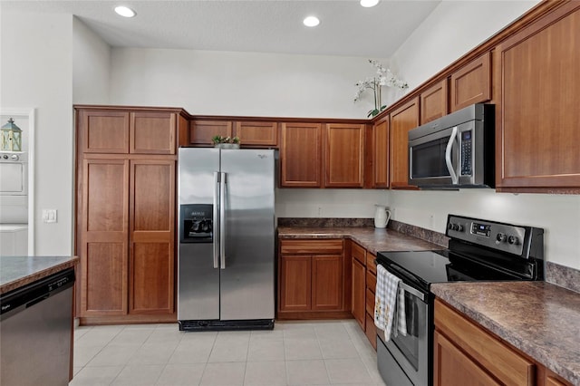 kitchen with light tile patterned flooring, stacked washer and clothes dryer, and appliances with stainless steel finishes