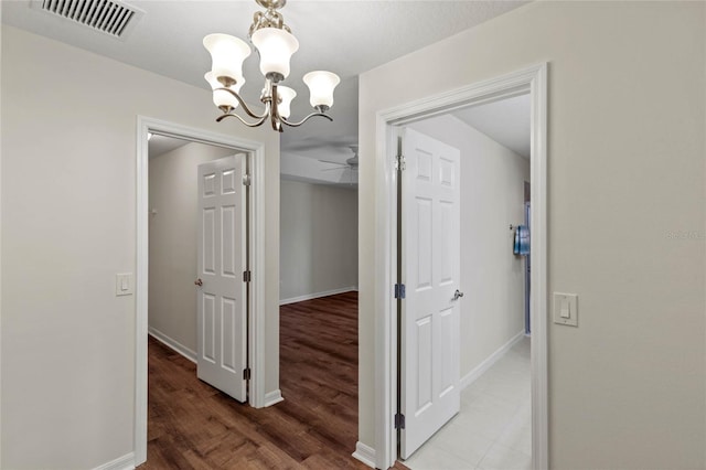 corridor featuring an inviting chandelier and hardwood / wood-style flooring