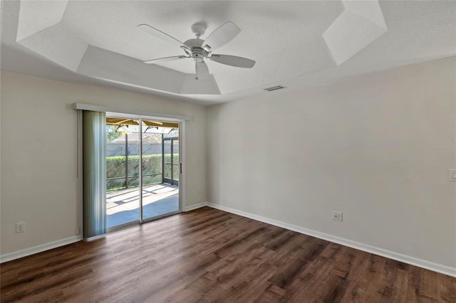 spare room featuring ceiling fan, a tray ceiling, dark wood-type flooring, and a textured ceiling