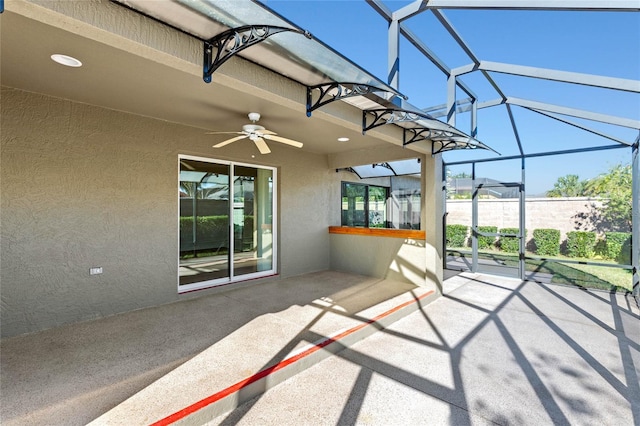 view of patio with ceiling fan and glass enclosure