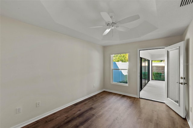 empty room featuring ceiling fan, wood-type flooring, and a raised ceiling