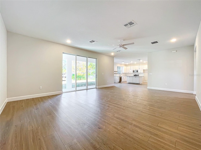 unfurnished living room featuring ceiling fan and light hardwood / wood-style floors