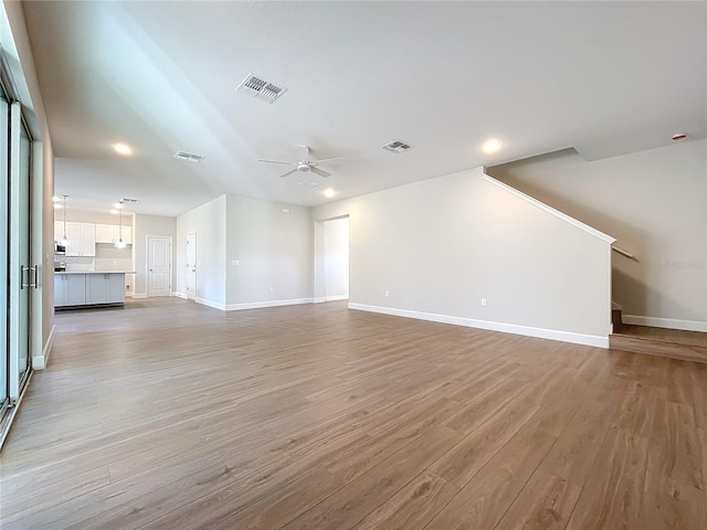 unfurnished living room featuring ceiling fan and light wood-type flooring