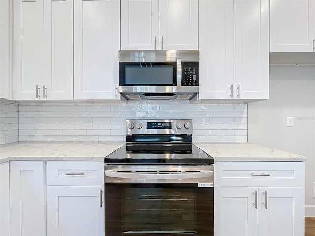 kitchen featuring white cabinets, appliances with stainless steel finishes, decorative backsplash, and light stone counters