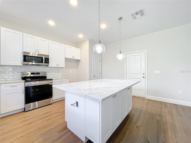 kitchen with a center island, white cabinetry, stainless steel appliances, and hanging light fixtures