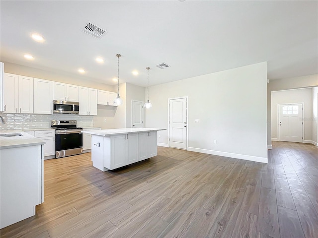 kitchen with light hardwood / wood-style floors, white cabinetry, and appliances with stainless steel finishes