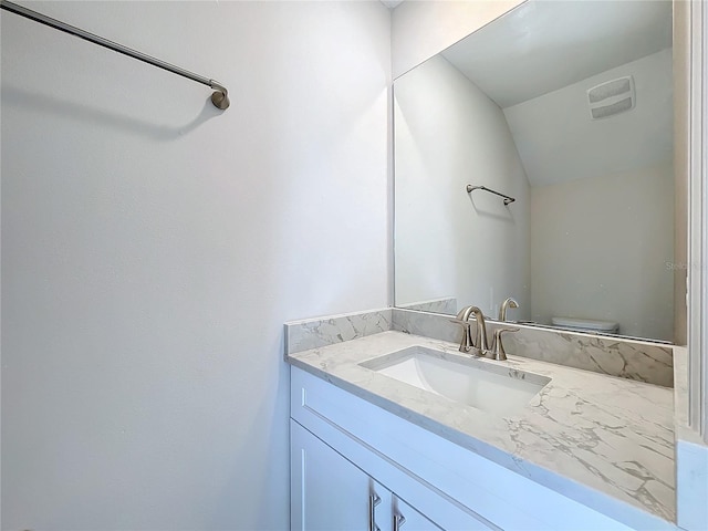 bathroom featuring vanity, toilet, and lofted ceiling