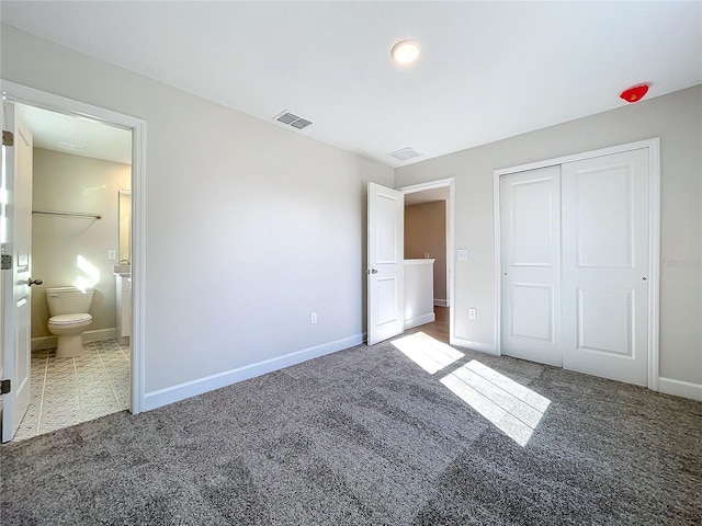 unfurnished bedroom featuring ensuite bath, carpet floors, and a closet