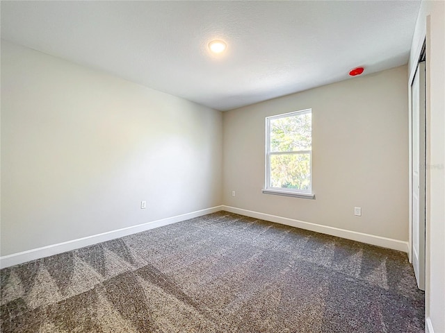 unfurnished room with dark colored carpet