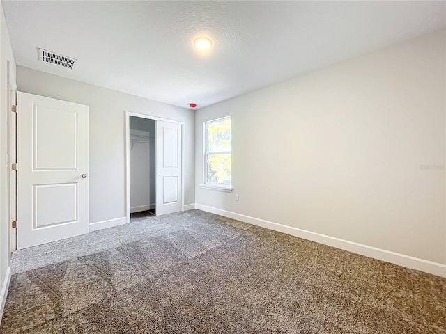 unfurnished bedroom with carpet, a textured ceiling, and a closet