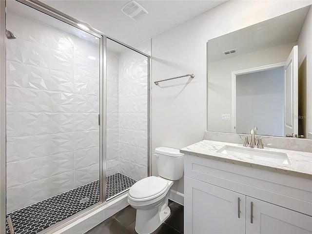 bathroom with tile patterned floors, vanity, toilet, and a shower with shower door